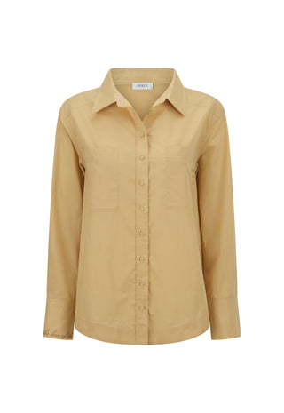A woman wearing an oversized tan long-sleeve shirt and dark shorts
