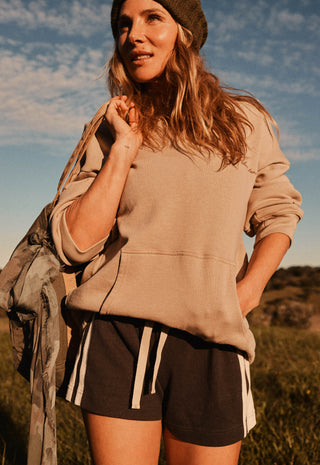A woman outdoors wearing a beige oversized sweatshirt