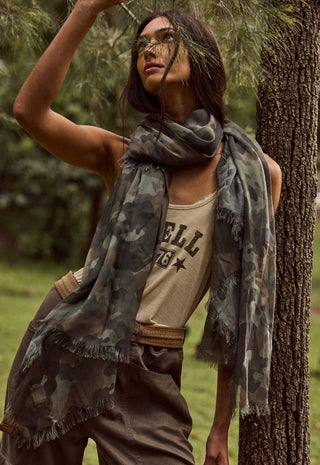 front-view-of-camo-green-modal-travel-scarf-with-frayed-edges-draped-loosely-around-models-neck-outdoors